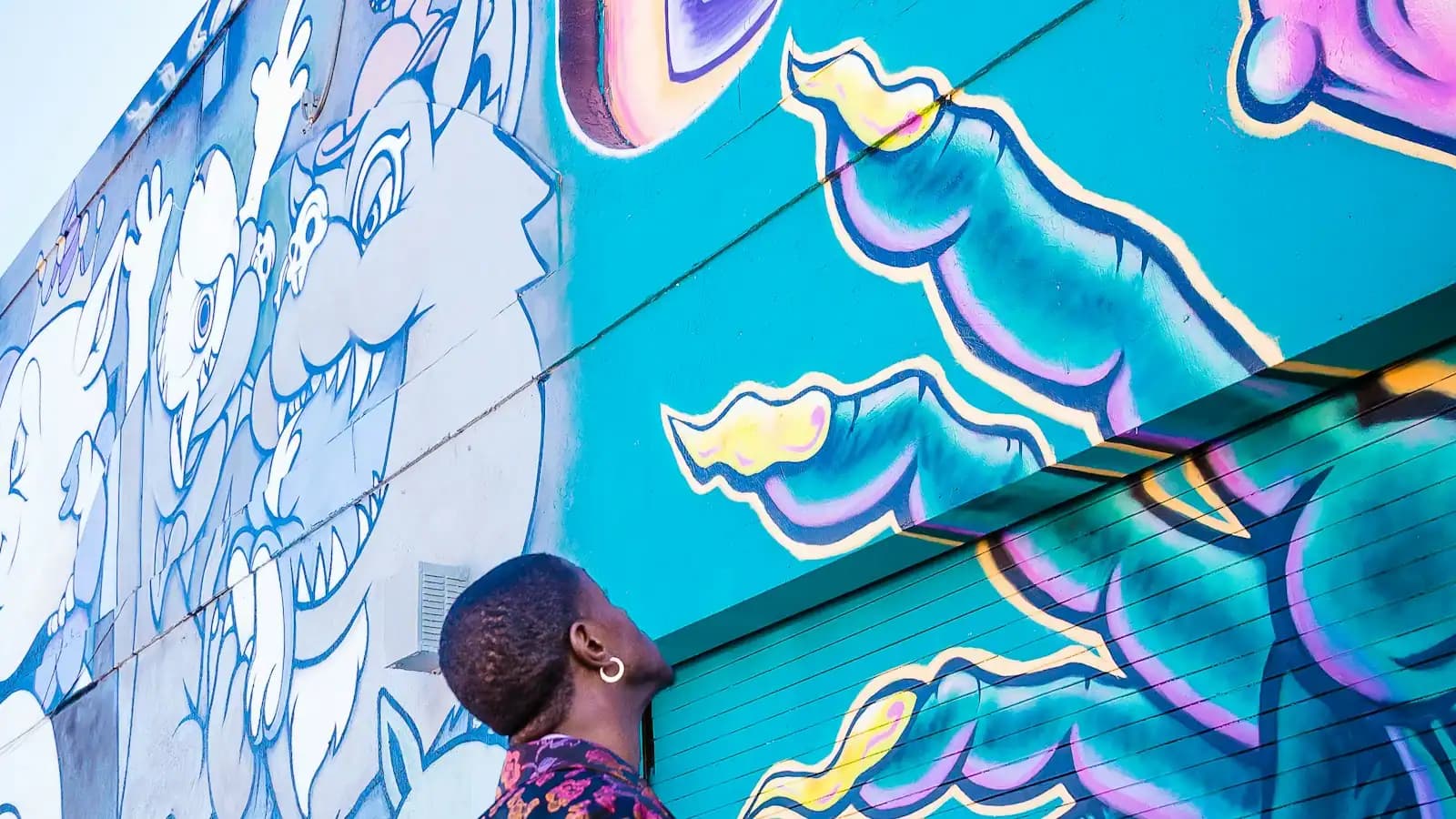 A visitor looking up at a large painted mural covering a wall in the Wynwood arts district of Miami