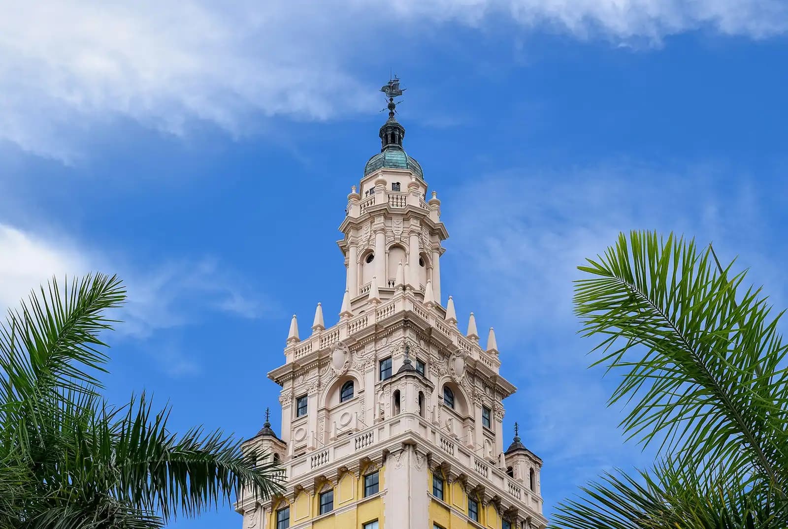 An ornate 1920s tower with a decorated crown standing among much taller modern glass buildings