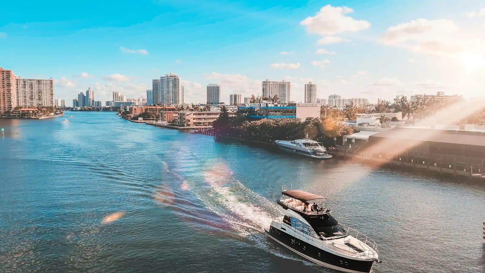 A motor yacht heading down an intracoastal waterway in Miami with residential high-rise towers along the shore